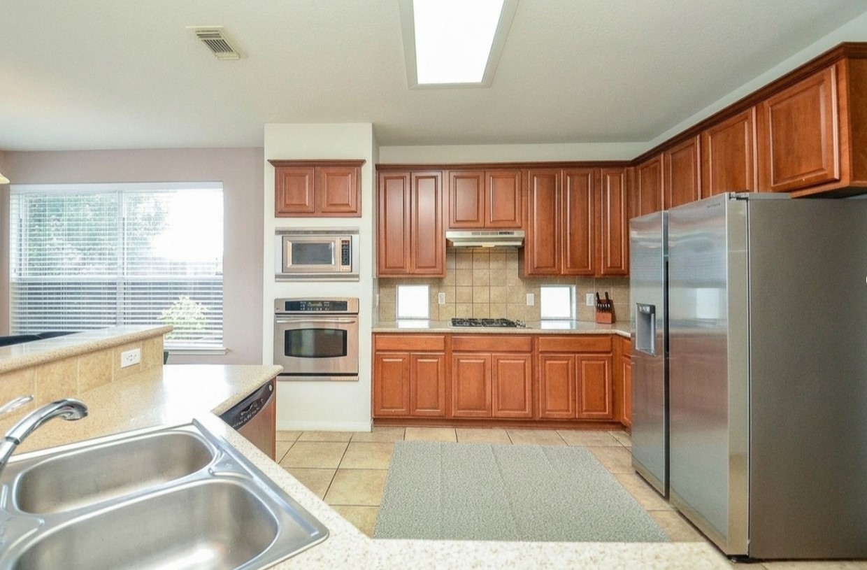 19802 Shavon Springs Drive Spring, TX 77388 - Photo 15 of 30 Spacious kitchen featuring sleek stainless steel appliances, rich wood cabinetry, and ample natural light. Perfect for culinary enthusiasts and family gatherings.