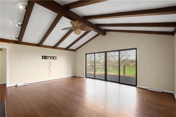 a view of a hallway with wooden floor and windows