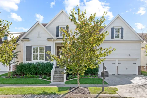 a front view of a house with a garden and trees