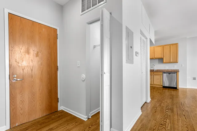 a view of a hallway with wooden floor and a bathroom