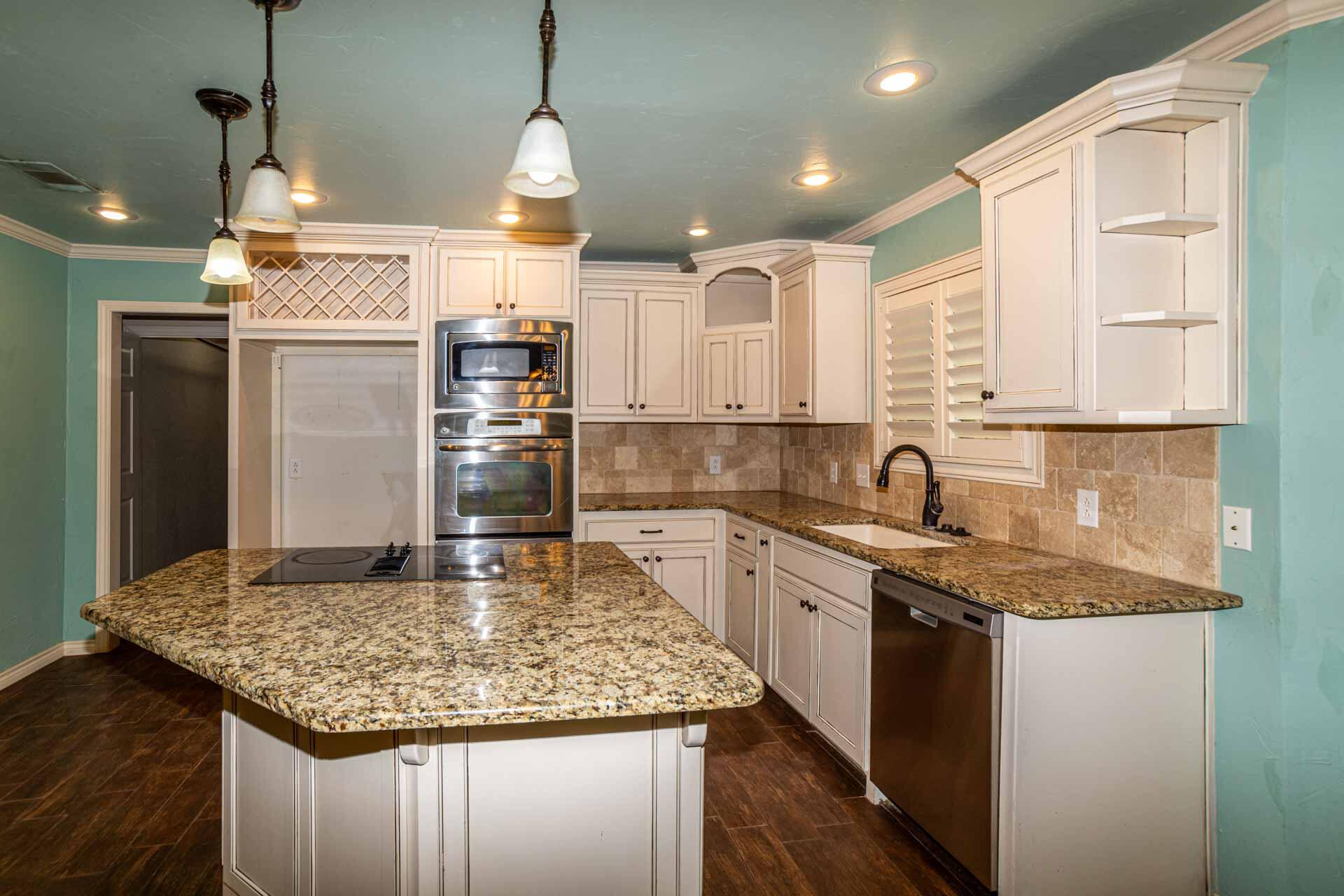 3312 77th Street Lubbock, TX 79423 - Photo 13 of 30 a kitchen with kitchen island granite countertop a sink appliances and cabinets