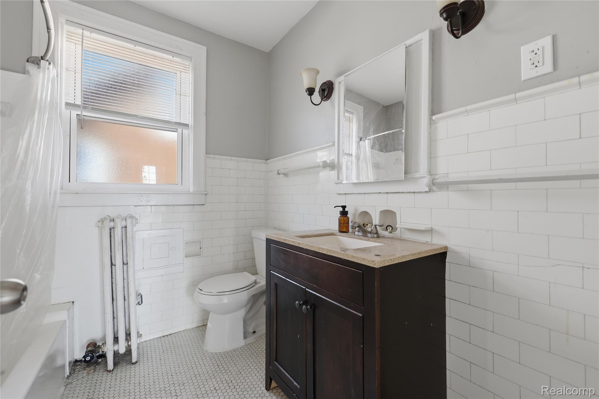 1945 Atkinson Street Detroit, MI 48206 - Photo 33 of 49 Bathroom featuring white subway tile wainscoting, a dark wood-finish vanity with a light-toned countertop, and a white hexagon mosaic tile floor
