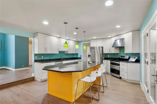 a kitchen with stainless steel appliances granite countertop a sink a stove a refrigerator and a oven