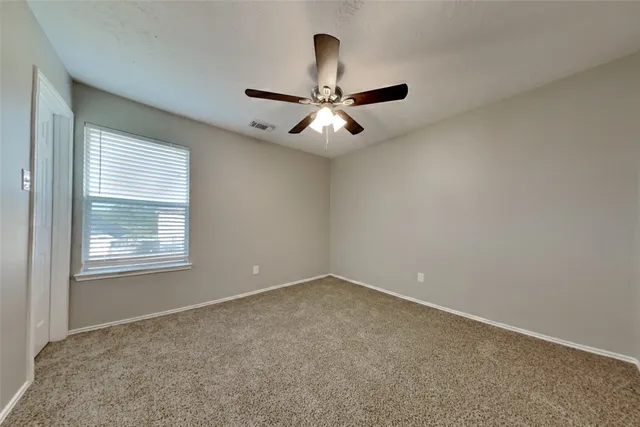 an empty room with a window and a fan