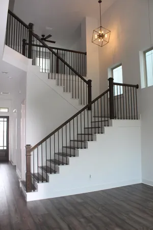 a view of staircase with railing and a chandelier