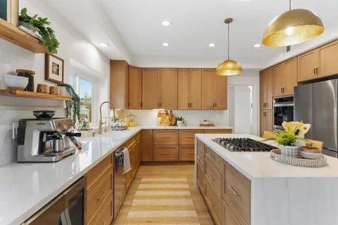 a kitchen with kitchen island granite countertop a sink a counter space and cabinets