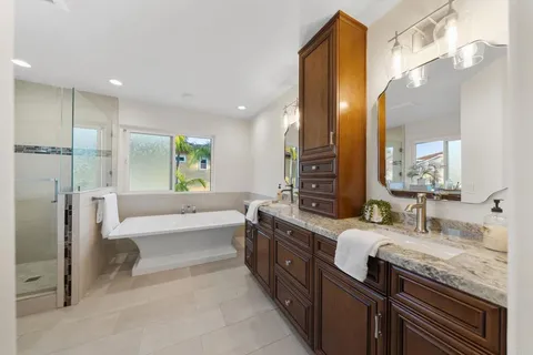 a bathroom with a granite countertop double vanity sink a mirror and a bathtub