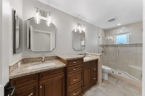 a bathroom with a granite countertop double vanity sink and mirror