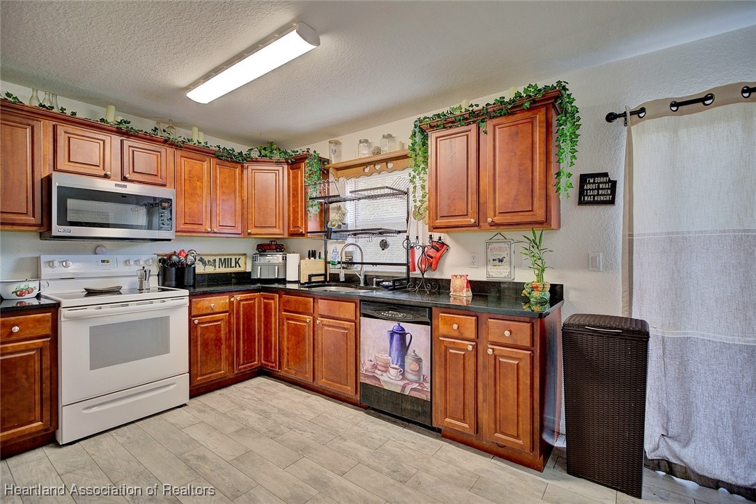 1700 Schlosser Road Sebring, FL 33870 - Photo 12 of 40 a kitchen with stainless steel appliances granite countertop a stove sink and microwave
