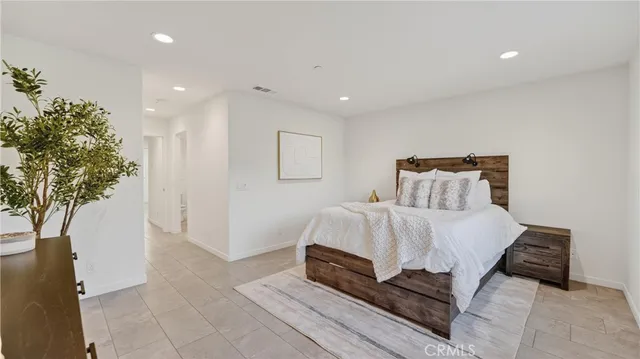 a bedroom with a large bed and a potted plant