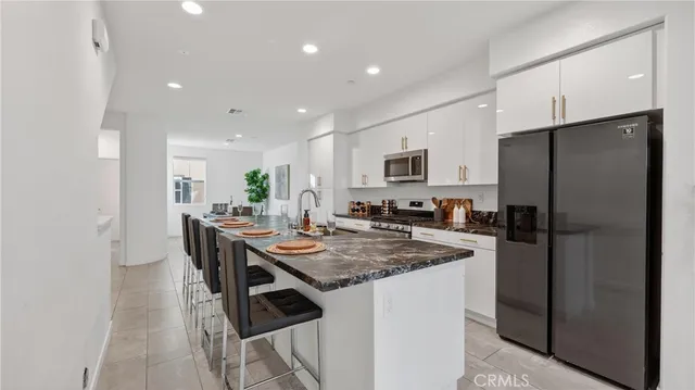 a kitchen with a refrigerator a stove a sink a dining table and chairs