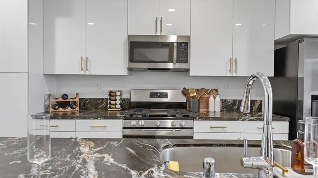 a kitchen with stainless steel appliances granite countertop a stove a sink and a microwave