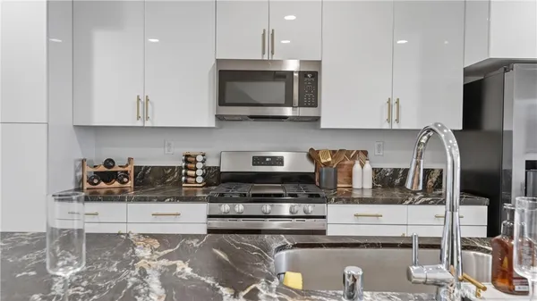 a kitchen with stainless steel appliances granite countertop a stove a sink and a microwave