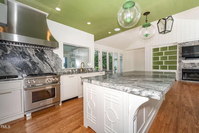 a kitchen with stainless steel appliances granite countertop a sink a stove and a wooden floors