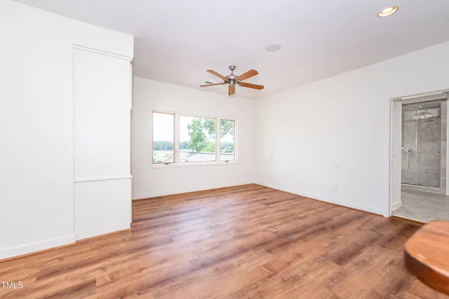 a view of empty room with wooden floor and fan