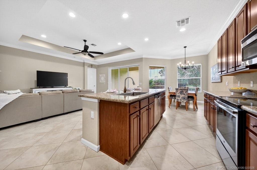 8121 Southwest Marin Drive Stuart, FL 34997 - Photo 11 of 31 a kitchen with stainless steel appliances kitchen island granite countertop a sink and a stove