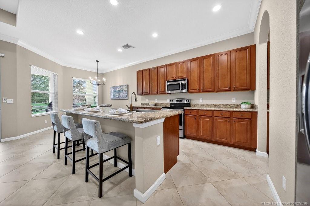 8121 Southwest Marin Drive Stuart, FL 34997 - Photo 12 of 31 a kitchen with stainless steel appliances granite countertop wooden cabinets a table and chairs