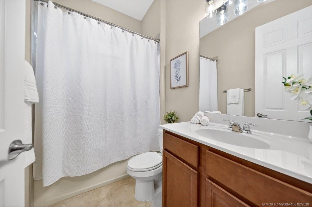 8121 Southwest Marin Drive Stuart, FL 34997 - Photo 21 of 31 a bathroom with a sink a toilet and shower curtain