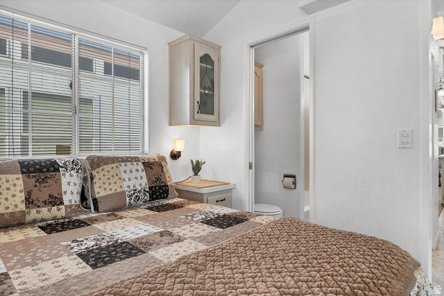 2990 East Riverside Drive, Unit 173 St. George, UT 84790 - Photo 12 of 38 Bedroom featuring a window with horizontal blinds, overhead cabinetry with glass inserts, and a wall-mounted light fixture