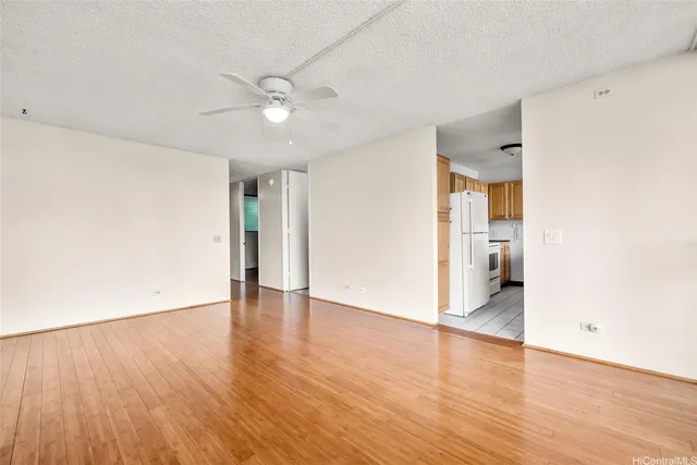 an empty room with wooden floor and a ceiling fan