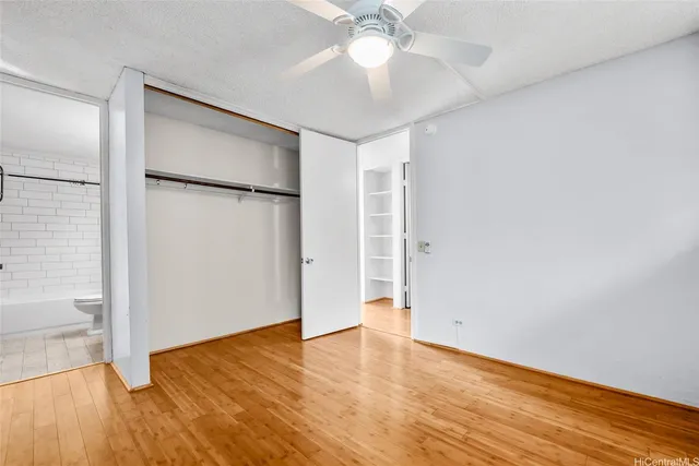 an empty room with wooden floor and a ceiling fan