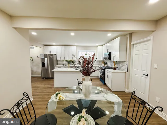 a kitchen with stainless steel appliances granite countertop a kitchen island a stove a sink a dining table and chairs