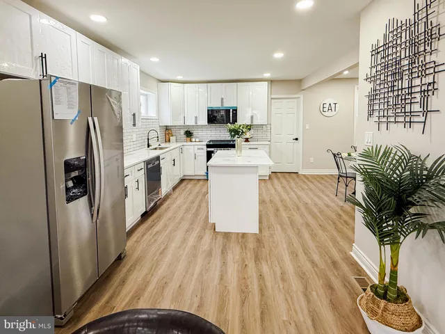 a kitchen with stainless steel appliances granite countertop a refrigerator a stove a sink dishwasher and a refrigerator with wooden floor