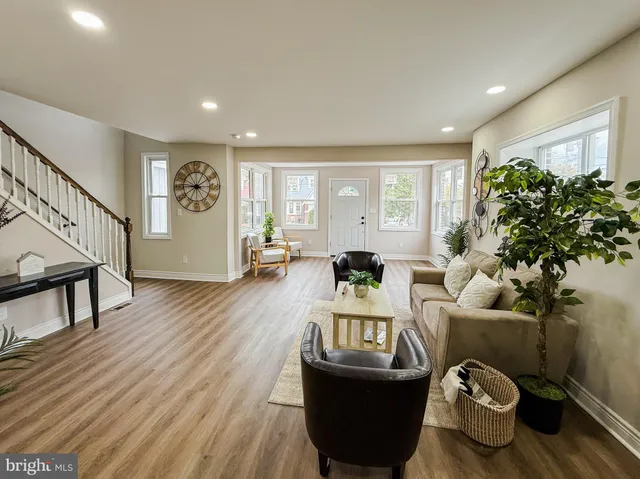 a living room with furniture a potted plant and a wooden floor