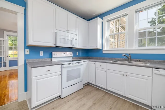 a kitchen with granite countertop white cabinets sink and window