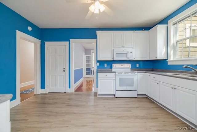 a kitchen with stainless steel appliances granite countertop a stove a sink and white cabinets
