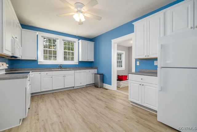 a kitchen with wooden floors and white cabinets