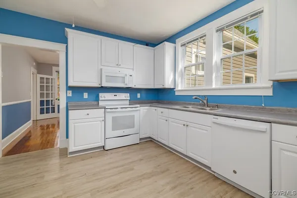 a kitchen with granite countertop white cabinets and white appliances