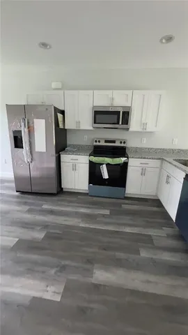 a kitchen with stainless steel appliances kitchen island granite countertop a stove and white cabinets