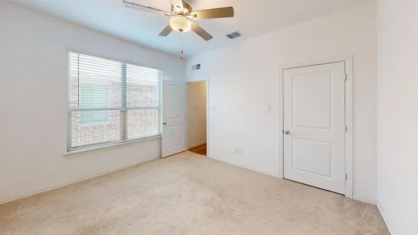 an empty room with windows and fan