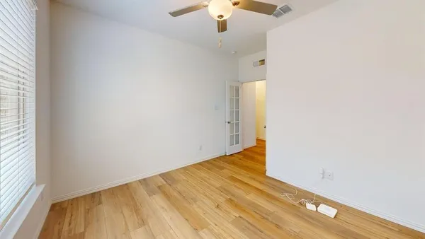 an empty room with wooden floor fan and windows