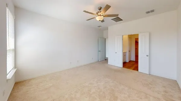 an empty room with a window and a ceiling fan