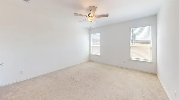 an empty room with a window and a ceiling fan