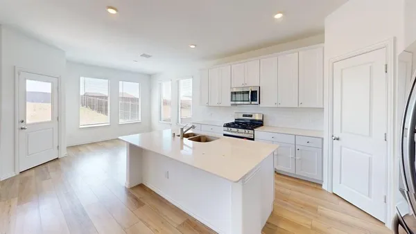 a kitchen with a sink a stove a refrigerator cabinets and a window