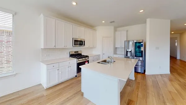 a kitchen with kitchen island a white counter top space a sink a stove and a refrigerator