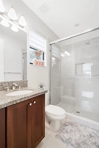 a bedroom with a bed a chair and potted plant on the dresser