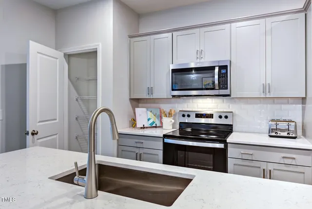 a kitchen with stainless steel appliances a stove a sink a microwave and cabinets