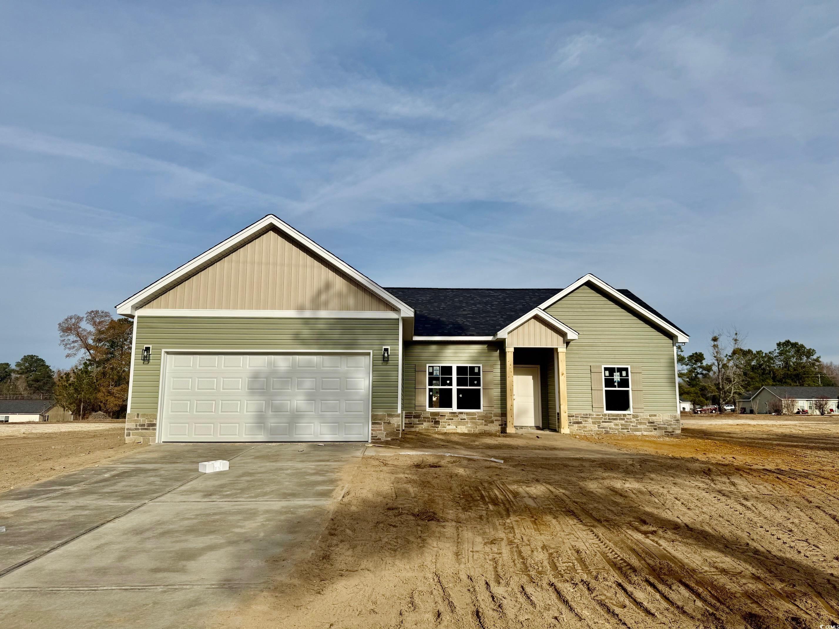 View of front of home featuring stone siding, driveway, and a garage
