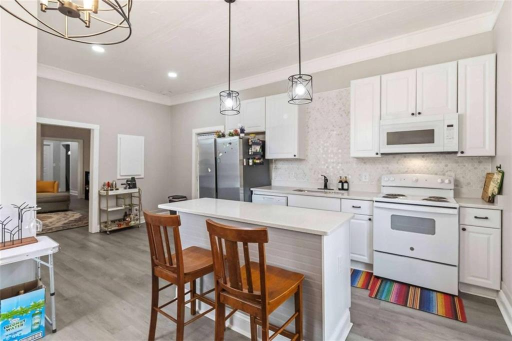 949 East Solomon Street Griffin, GA 30223 - Photo 9 of 26 a kitchen with stainless steel appliances a stove a sink refrigerator dining table and chairs with wooden floor