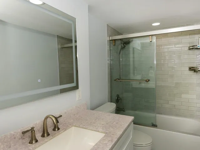 a bathroom with a granite countertop sink toilet and shower