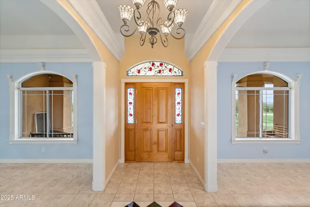 a view of a livingroom with a fireplace a chandelier and windows