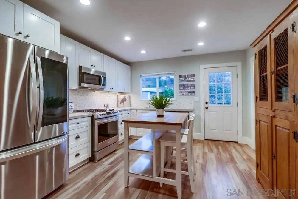 11461 Posthill Place Lakeside, CA 92040 - Photo 17 of 46 a kitchen with stainless steel appliances a microwave a stove a refrigerator white cabinets and wooden floor