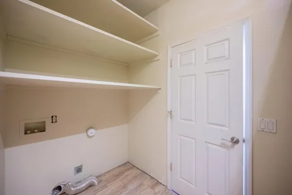 a view of empty room with wooden floor and bathroom