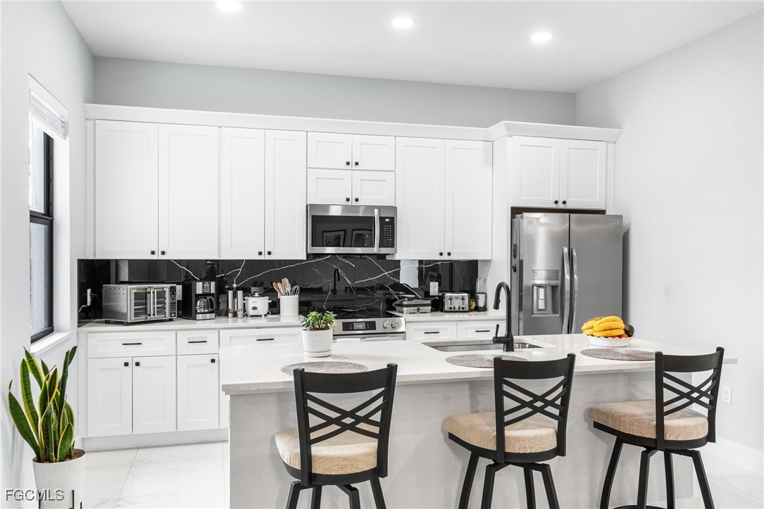 7583 15th Place LaBelle, FL 33935 - Photo 20 of 34 a kitchen with stainless steel appliances kitchen island granite countertop a table chairs and a refrigerator