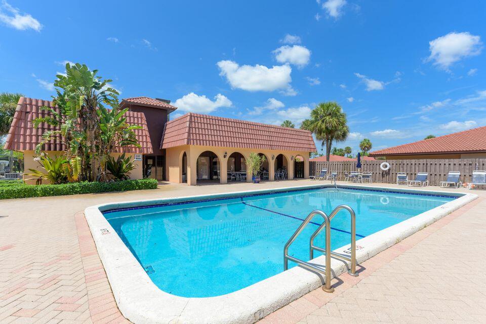 5939 Forest Hill Boulevard, Unit 205 West Palm Beach, FL 33415 - Photo 17 of 19 a view of a swimming pool with a lounge chairs