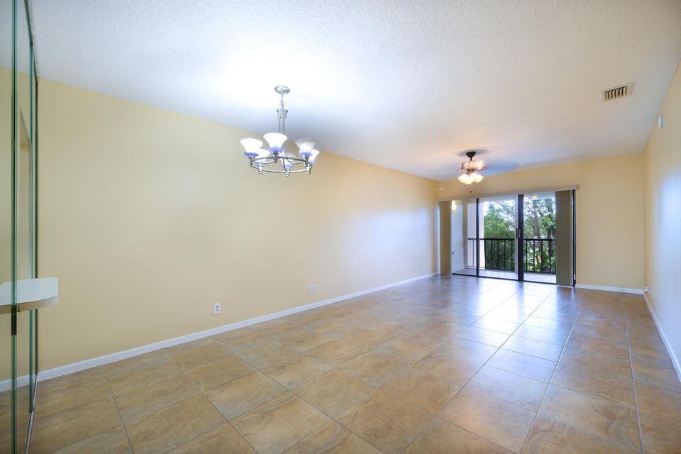 5939 Forest Hill Boulevard, Unit 205 West Palm Beach, FL 33415 - Photo 5 of 19 an empty room with chandelier and windows